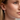 Close-up of a woman wearing an oyster-shaped drop earring and a small pearl stud.